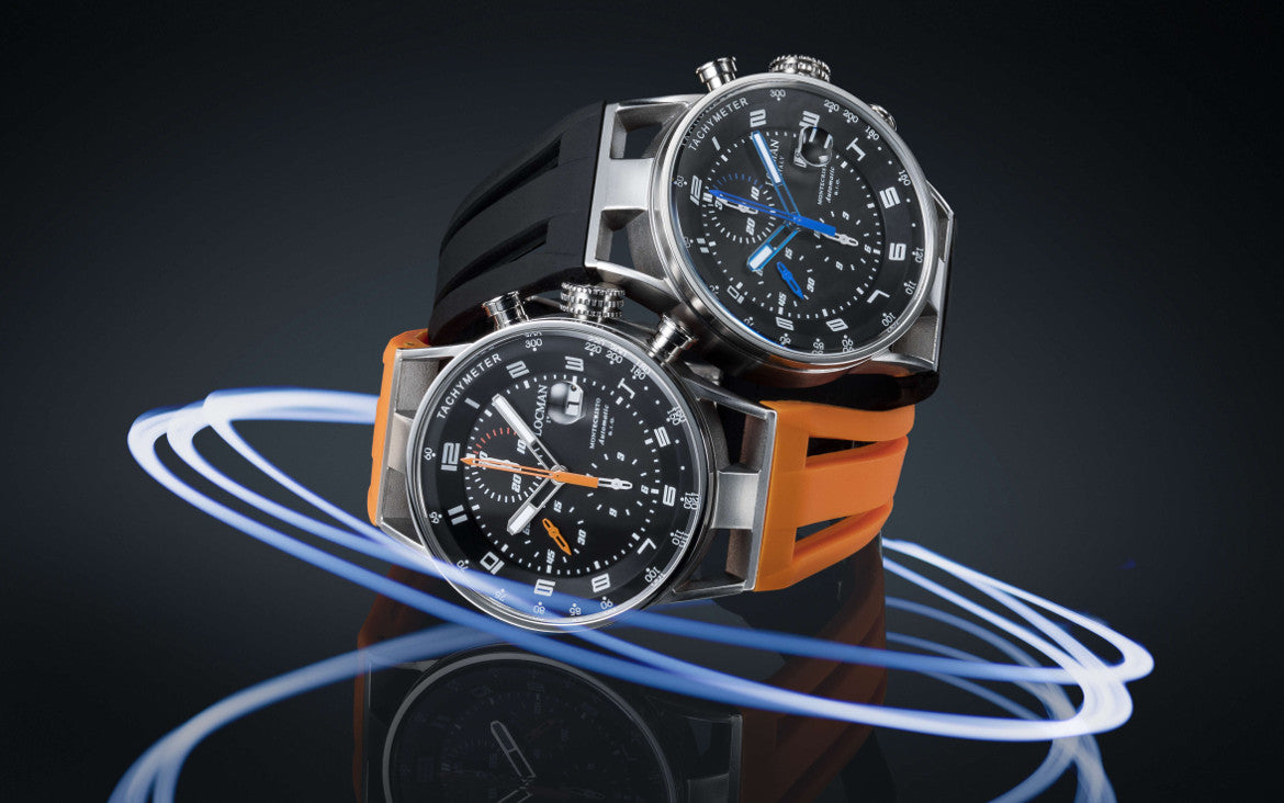 Two watches with black faces and orange straps on a reflective surface with a dark background