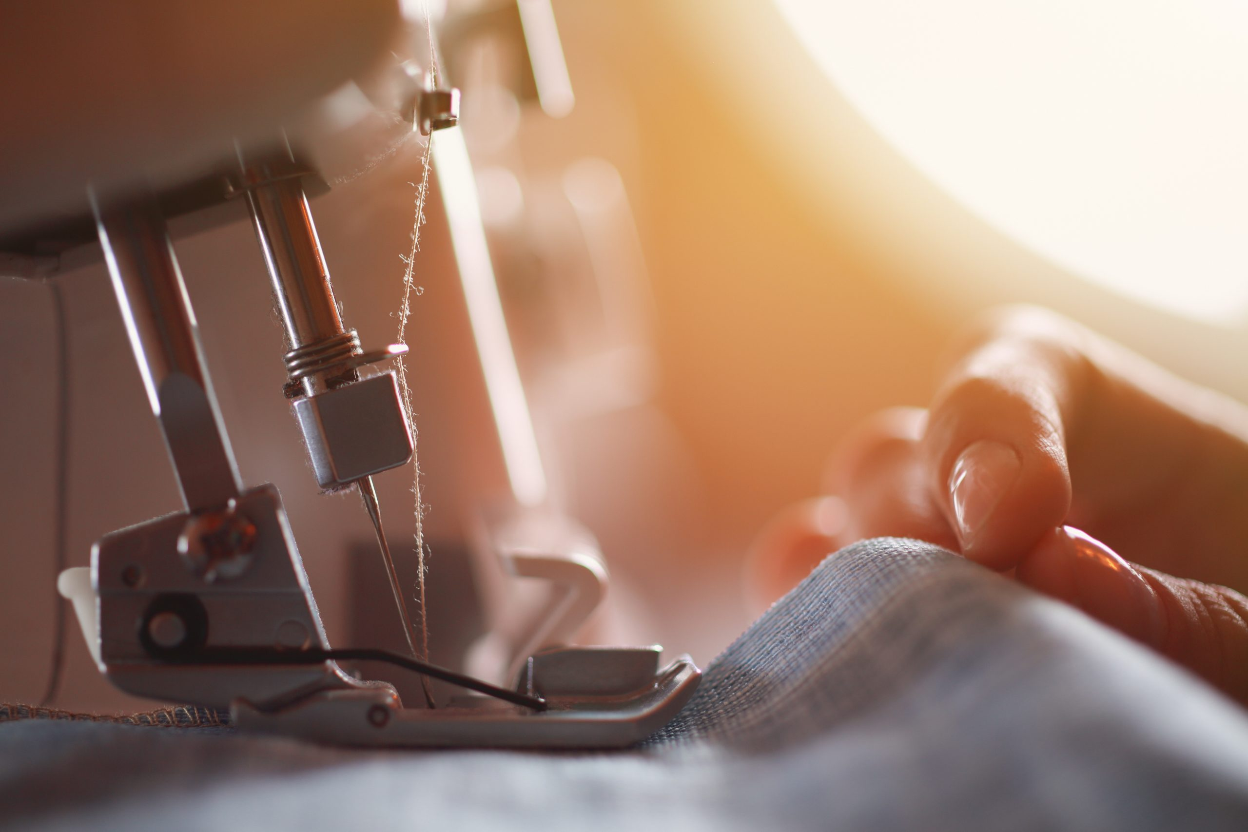 Close-up of a sewing machine needle piercing fabric with a blurred background